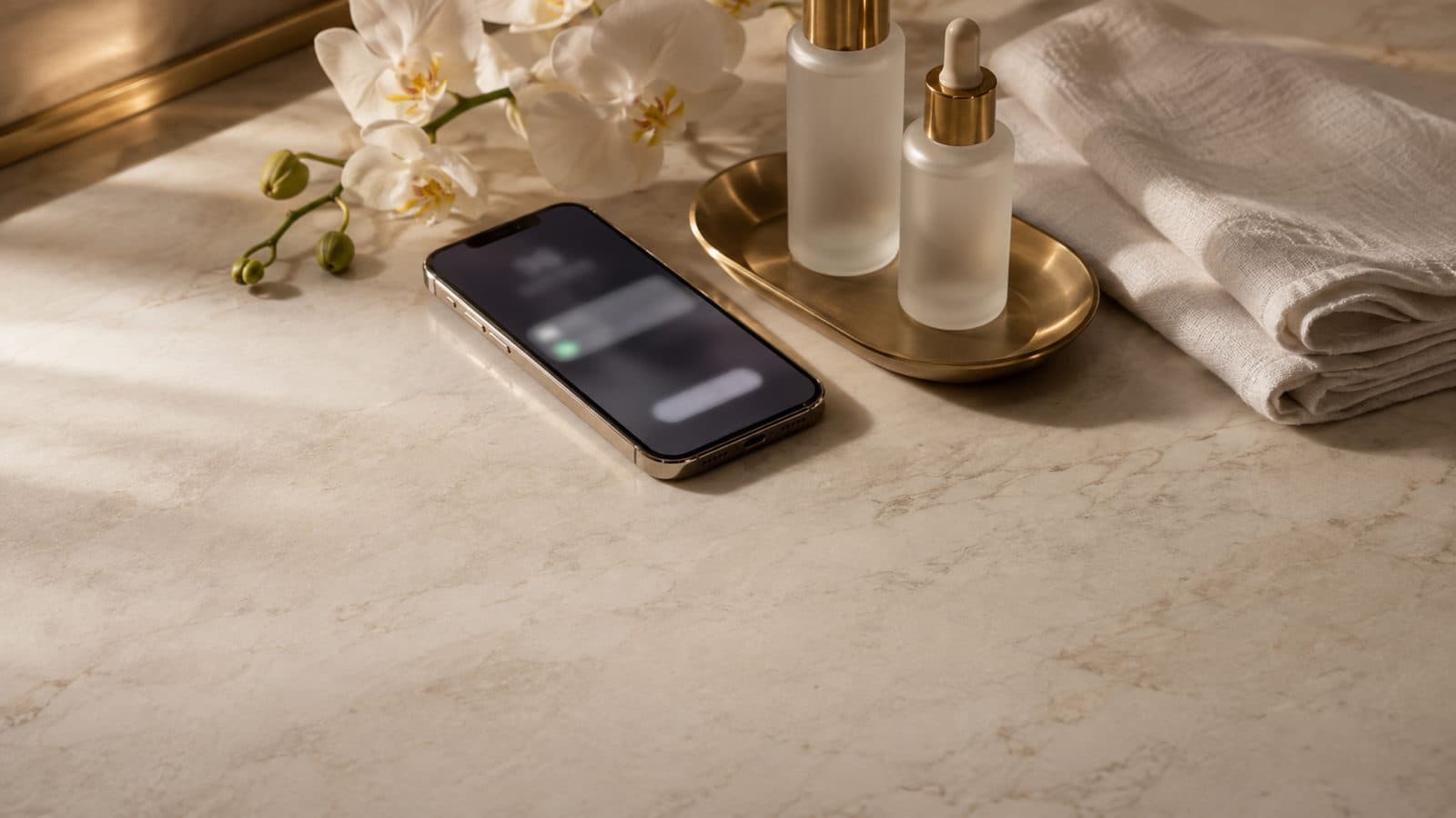 A phone left face up on a marble counter beside serums, a folded towel and orchids, its screen showing a call nobody answered.
